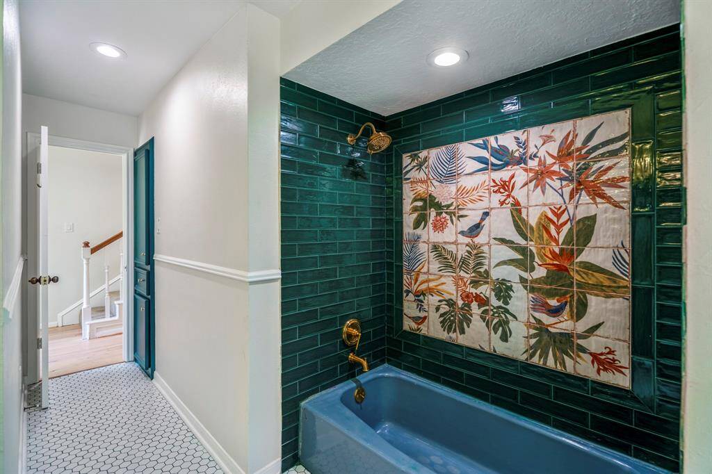 This bathroom features a spacious double vanity with marble countertops and elegant brass fixtures. Large windows provide abundant natural light, and the stylish lighting fixtures add a modern touch. The dark cabinetry contrasts beautifully with the light flooring, creating a chic and functional space.