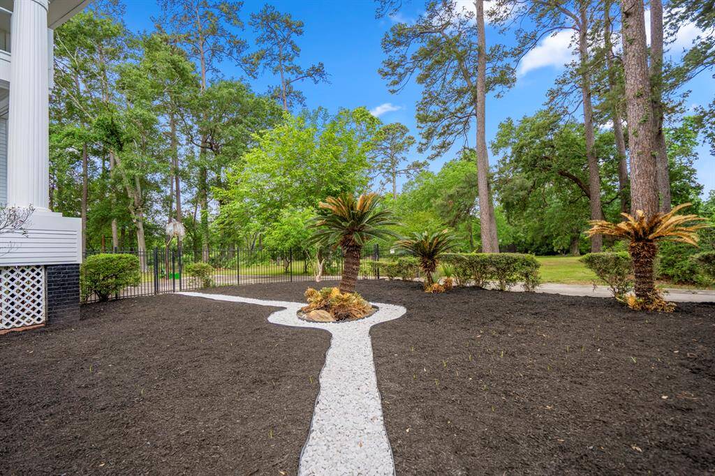 Imagine evenings spent on your front porch amidst a lush, wooded landscape. A long driveway leads to the property, surrounded by mature trees and well-maintained greenery, providing a serene and private setting.