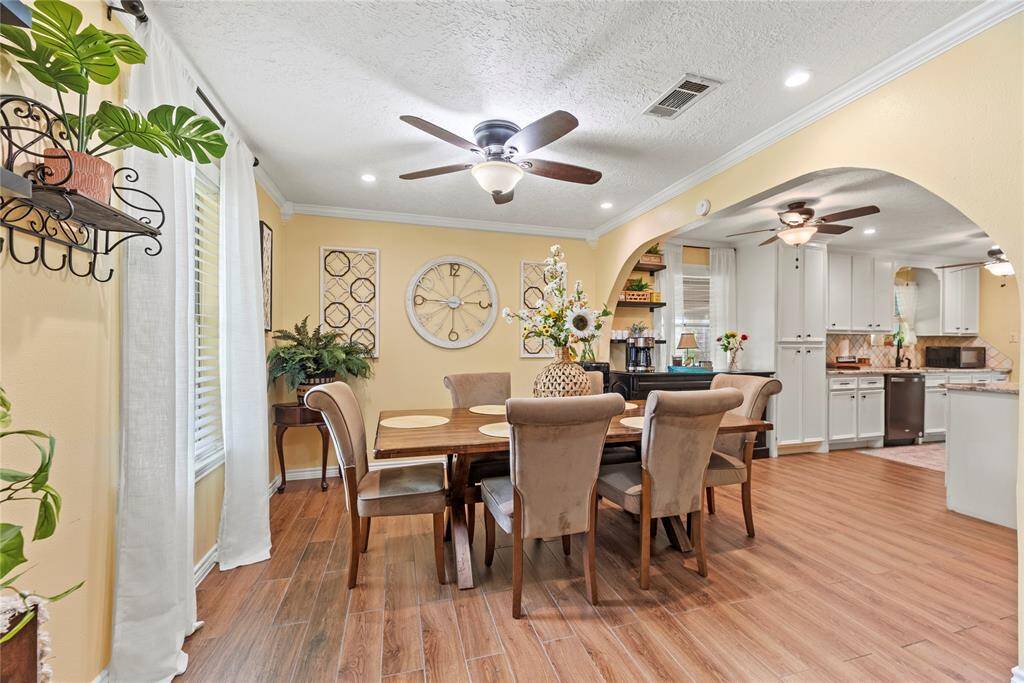 Charming dining area with crown molding, ceiling fan, and elegant archway transitions—perfect for hosting gatherings.