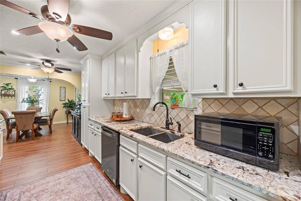 Additional kitchen view showcasing abundant cabinetry, modern appliances, and a double sink with a view.