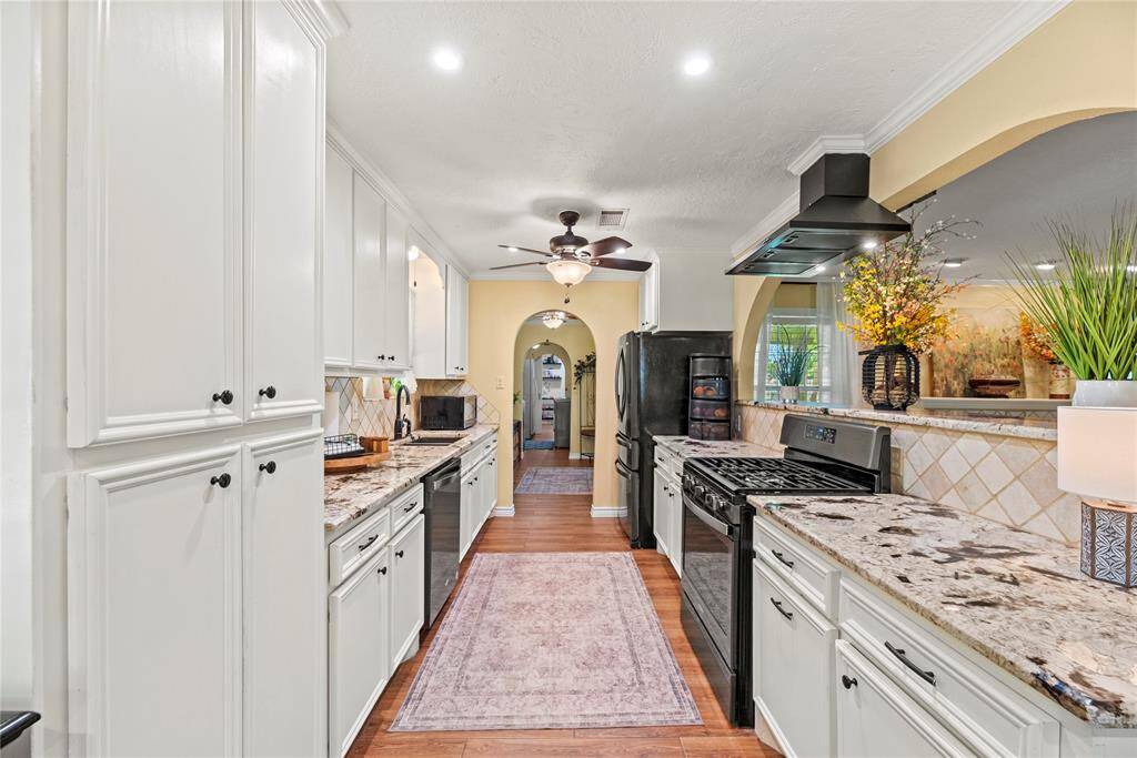 Full view of the galley-style kitchen with granite counters, tiled backsplash, and ample cabinet space.