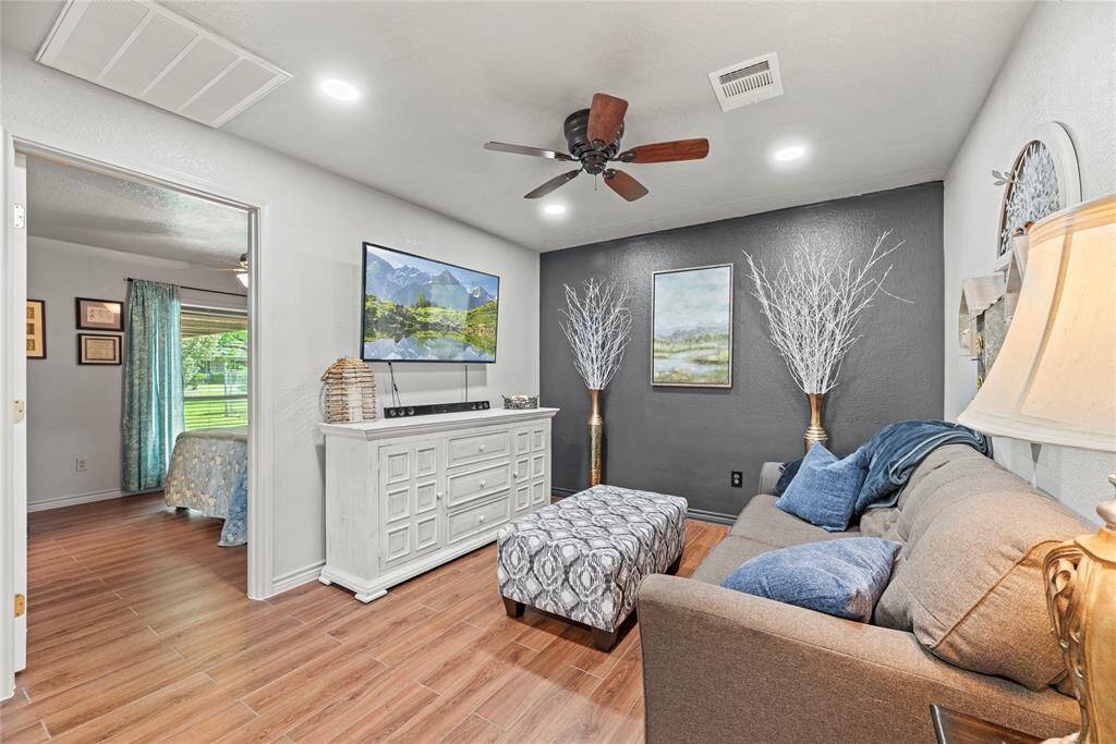 This stylish bonus space off of the primary suite features wood-look flooring, a deep charcoal accent wall, and built-in lighting, making it perfect for anextra lounge area.