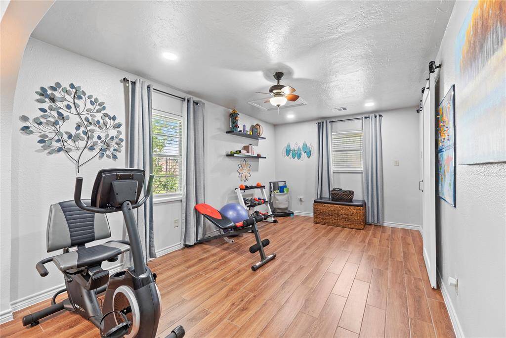 Versatile space off the primary suite currently used as a home gym, complete with built-in shelving and wood-look floors.