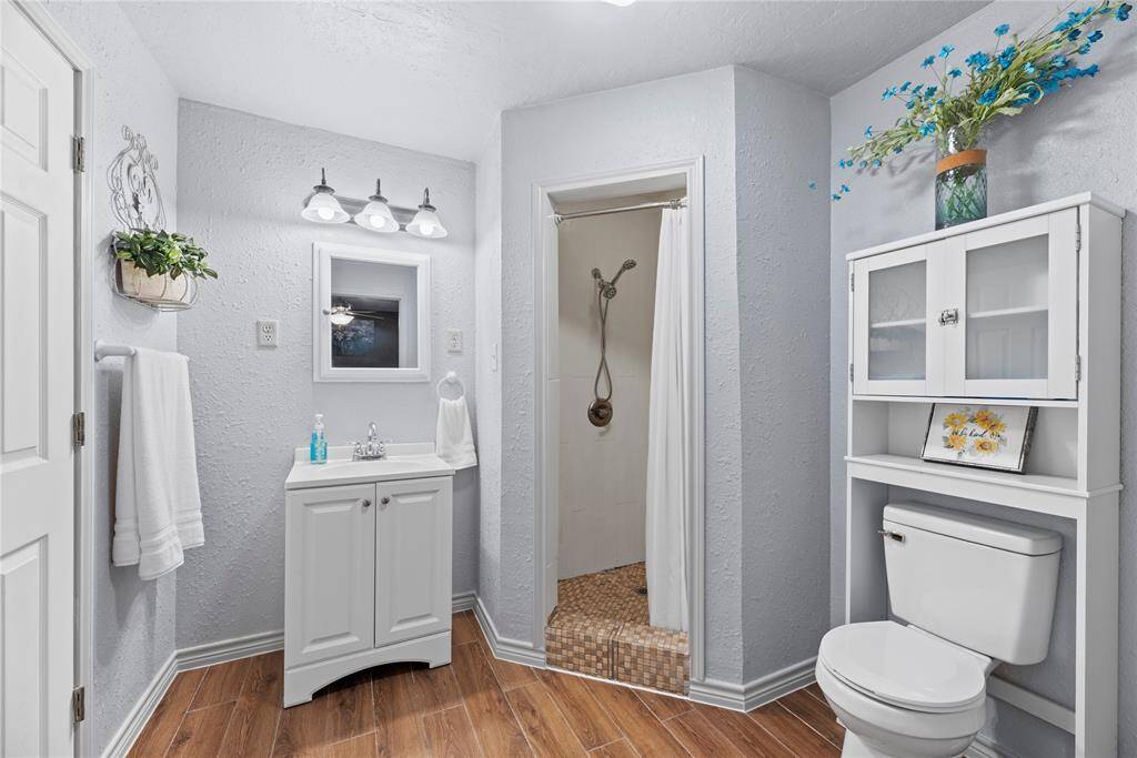 Bright and freshly updated, this bathroom includes a walk-in shower, sleek white vanity, and convenient storage cabinet with charming decorative accents.