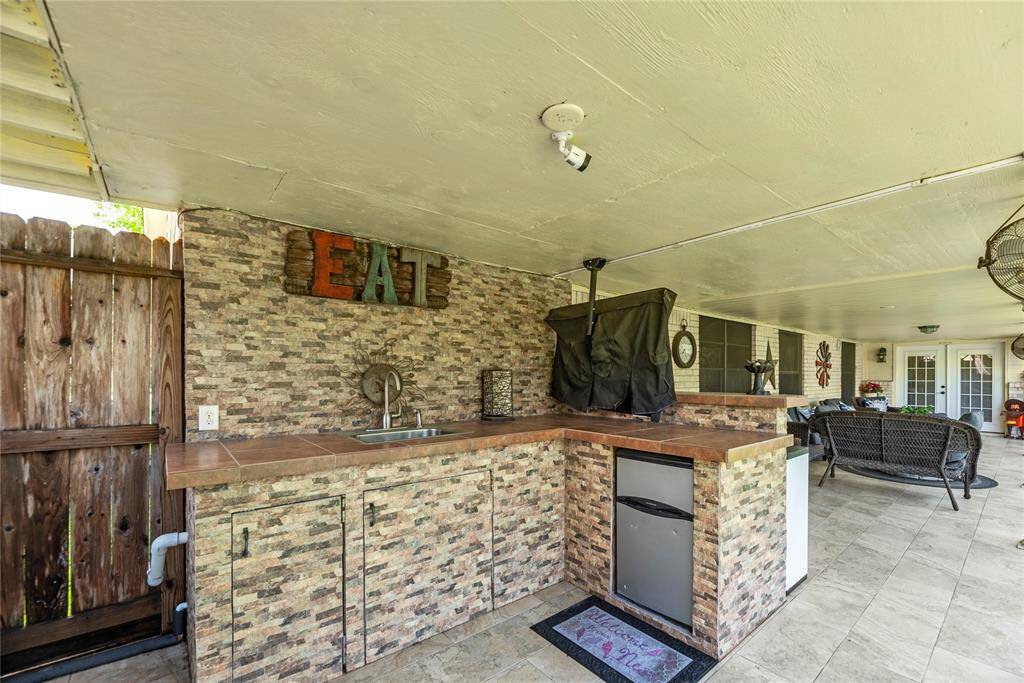 Custom-built outdoor kitchen featuring a sink, prep space, and mini-fridge. Great setup for weekend BBQs and summer gatherings.