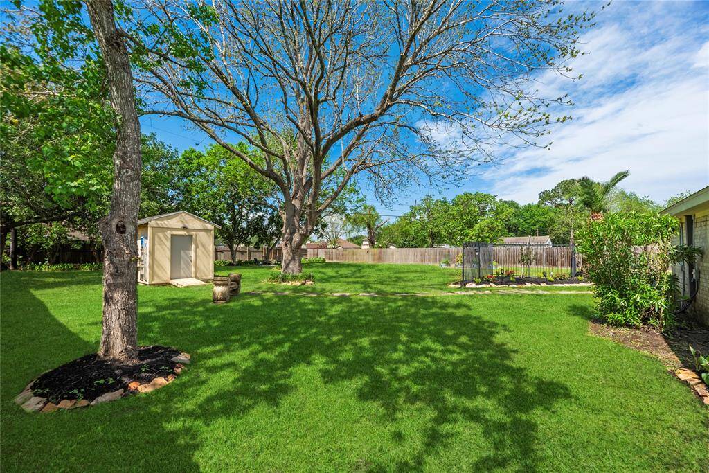 Spacious yard includes a handy storage shed and beautifully maintained landscaping with flower beds and decorative accents.