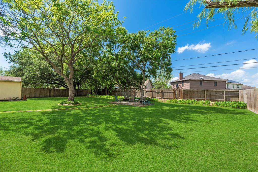 Another backyard angle showcasing a potential firepit area and additional seating under the trees, offering a peaceful retreat.