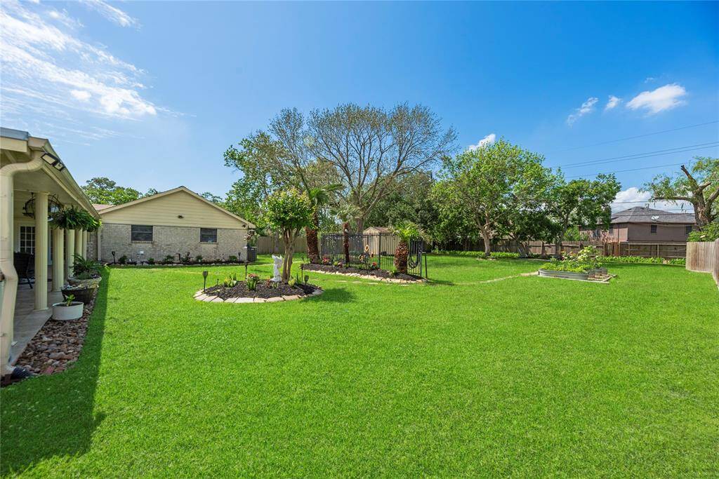 Oversized backyard with endless green space, mature trees, and raised garden beds—perfect for play, pets, or planting.