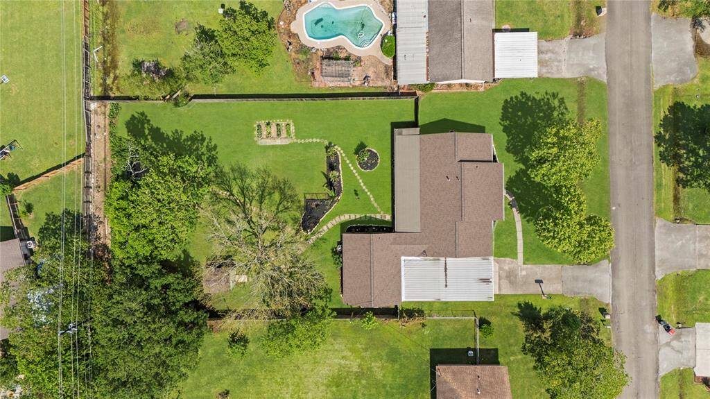 A top-down look at the beautifully landscaped backyard with raised garden beds, winding stone pathways, and mature trees providing shade and serenity.