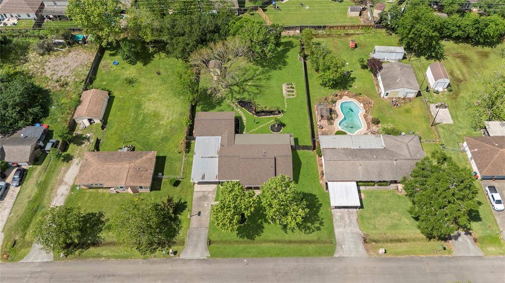 This wider aerial view shows the home’s prime lot placement with expansive backyard space, neighboring homes, and a community feel with tree-lined streets.