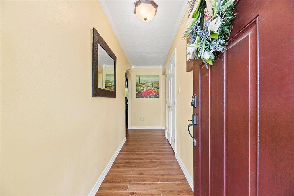 Step inside to a bright and inviting entry hallway with wood-look tile floors, crown molding, and a cozy feel that instantly says "home."