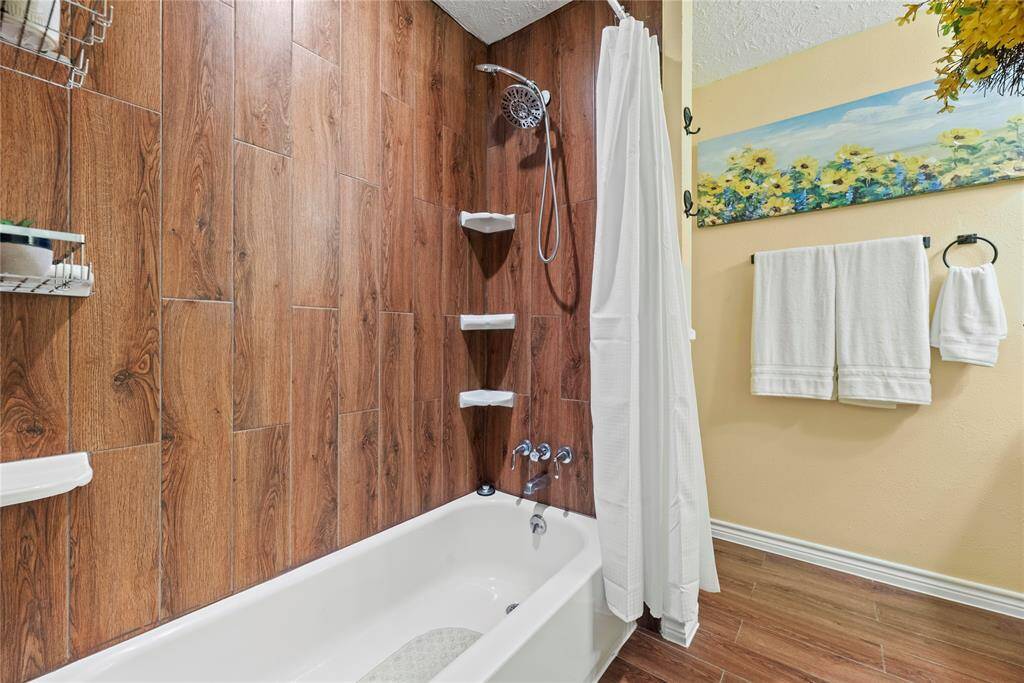Featuring rich wood-look tile walls and practical built-in shelving, this guest bath offers a stylish and functional space for relaxing soaks.