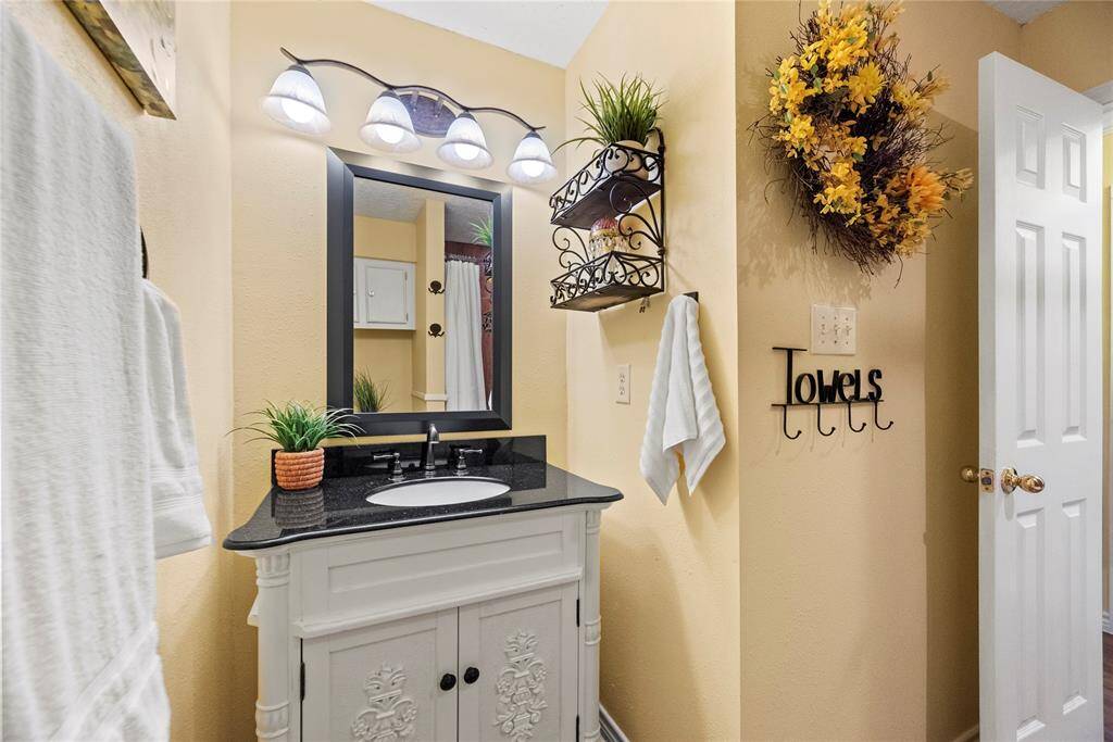 A charming bathroom complete with an elegant white vanity, black granite countertop, and decorative shelving—perfect for guests or daily use.