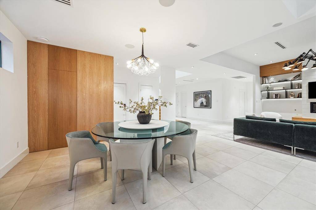Over the dining table is a modern globe chandelier that adds artistic flair.  An organized pantry sits behind the oak panels.