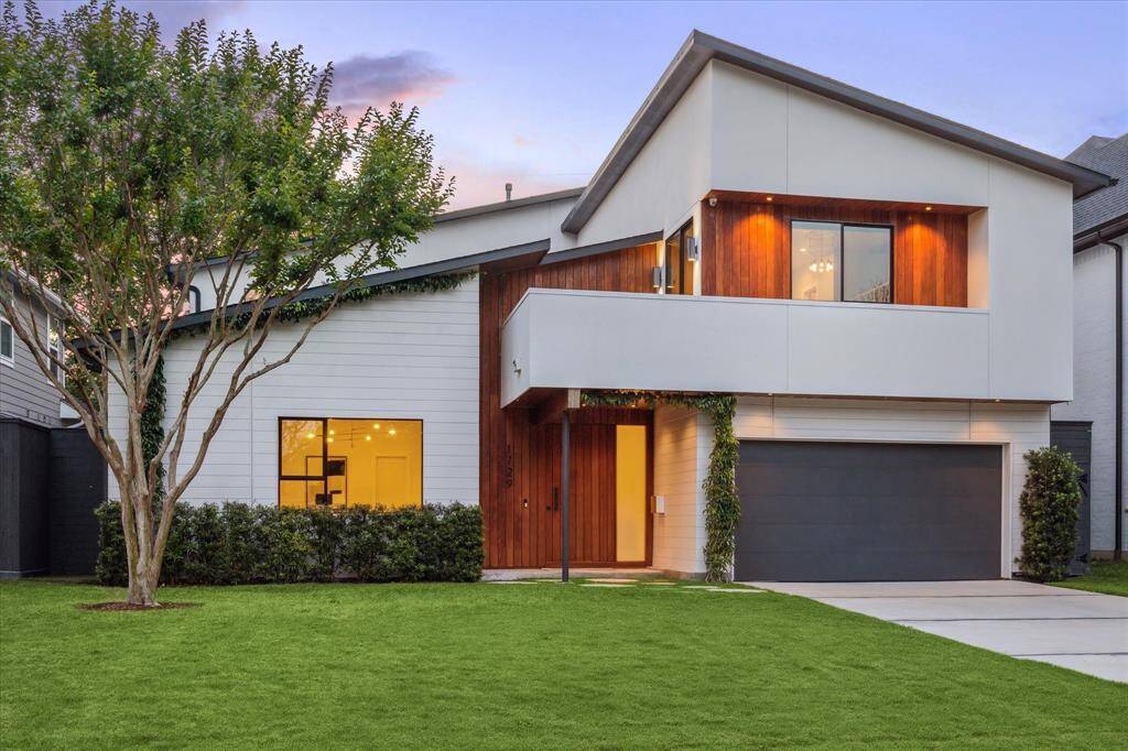 The two-story design is both eye-catching and inviting, featuring a prominent black garage door that adds contrast and sophistication to the facade.