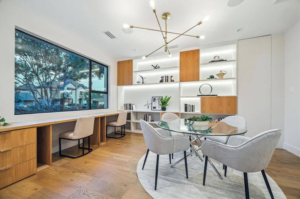Beautifully designed, light-filled study located downstairs, offering a serene view of the front yard through expansive picture windows. This versatile space features built-in dual workstations, ample custom cabinetry, and a striking wall of illuminated shelving—perfect for showcasing books, décor, or collectibles.