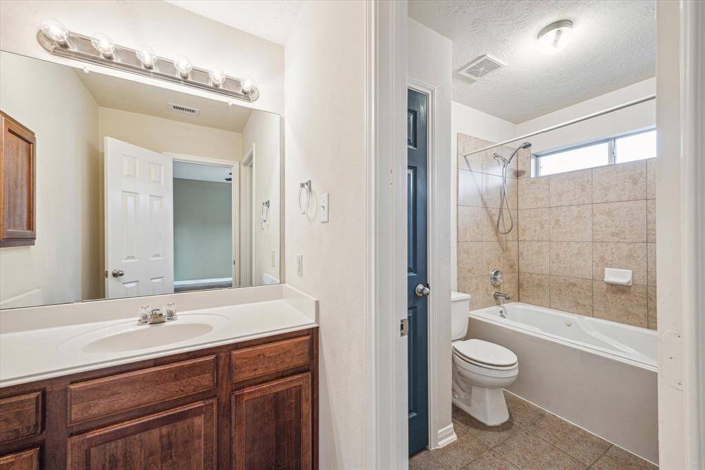 The en-suite primary bath has an expanded vanity with solid surface top and jetted tub/shower combo with transom window and ceramic tile surround.