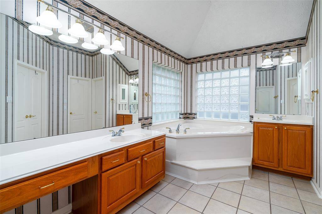 View in the primary bathroom of double sinks - one with a vanity and one taller.