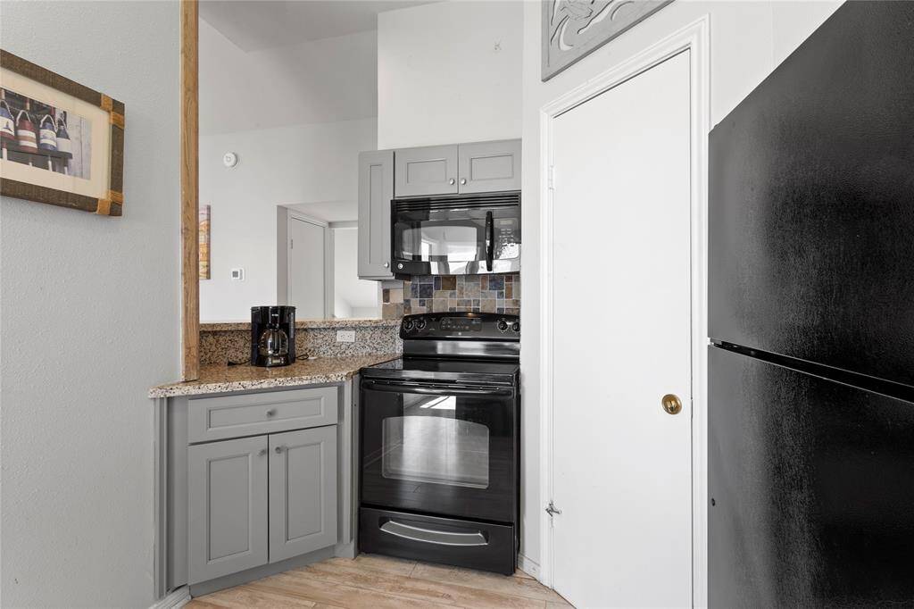 Updated kitchen with gray cabinetry and granite counter tops