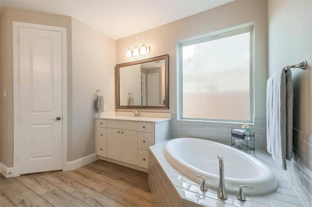 The primary bathroom is equipped with separate bathroom vanities with QUARTZ COUNTERS, large soaking tub under a frosted glass window and large walk-in shower.