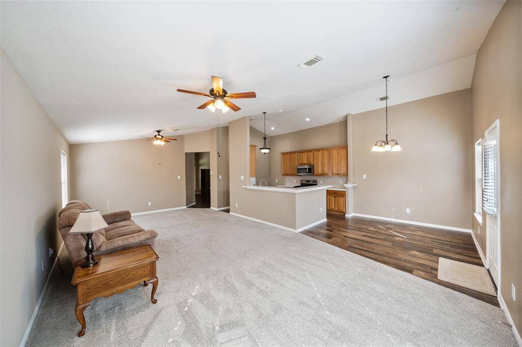 This oversized family room offers the perfect blend of comfort and style with a tall vaulted ceiling, neutral carpet and dual ceiling fans to keep things cool. The open layout flows easily into the kitchen and dining area, making everyday living and entertaining a breeze.