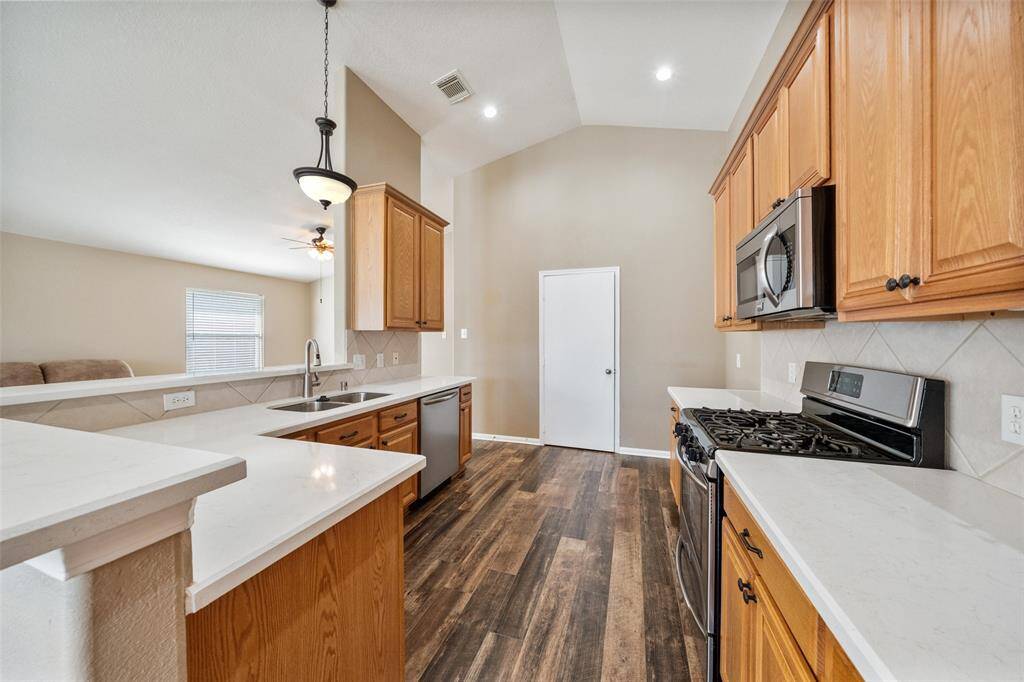 Show off your culinary skills in this immaculate kitchen featuring Quartz countertops and tile backsplash, rich wood cabinetry with updated pulls, sleek stainless steel appliances and a large pantry.