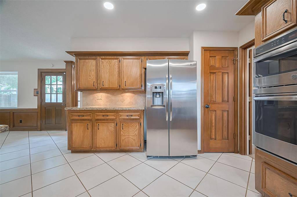 Opposite the kitchen sink, you'll find the sleek GE stainless steel French-style side-by-side refrigerator, with the added convenience of water and ice in the door—perfect for quick access. To the left, additional cabinet and countertop space offers room for all your cooking essentials, while to the right, the pantry provides easy access to dry goods. Updated LED lighting in the ceiling brightens the space, creating a warm, inviting atmosphere that’s both functional and efficient for your everyday needs.