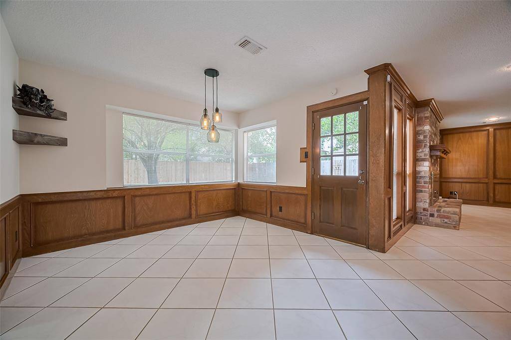 The breakfast area (13.6 x 11.0) features tile flooring and updated pendant lighting, creating a stylish and functional space. Picture-frame wood accent paneling along the lower wall adds warmth and charm. Large windows flood the room with natural light and offer a fantastic view of the backyard—perfect for keeping an eye on kids playing while preparing dinner or enjoying your morning coffee.