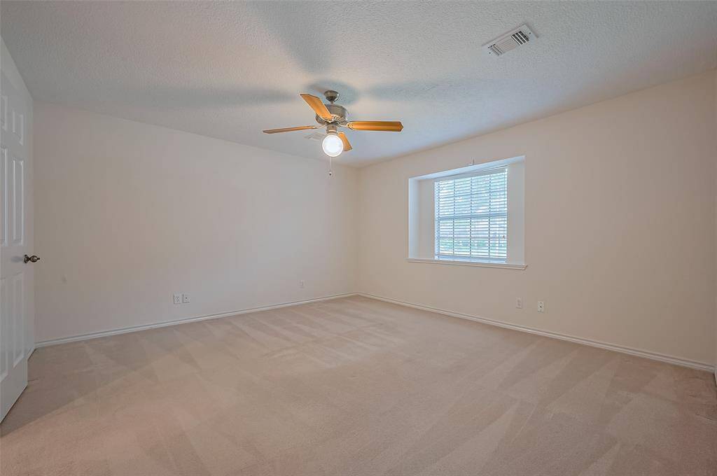The first-floor owner’s suite (15.1 x 13.3) offers comfort and convenience with soft carpet underfoot and a ceiling fan overhead. A charming box window overlooks the side yard, bringing in natural light while offering a quiet retreat. It’s a nicely sized room with plenty of space to relax and unwind.