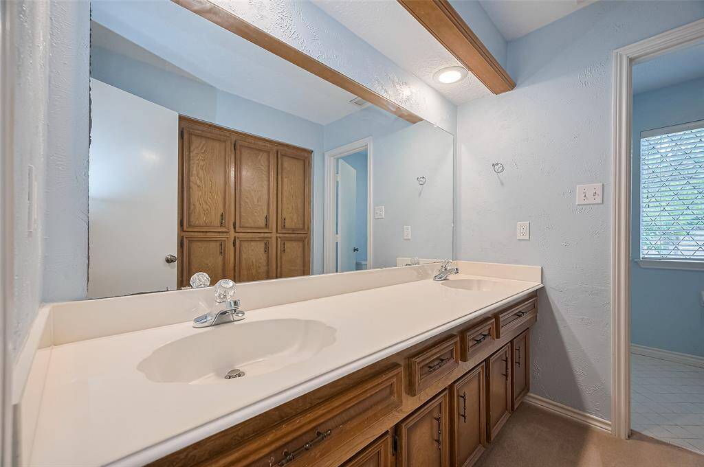 Across from the two sinks, you'll find an entire wall of built-ins—an incredible floor-to-ceiling storage space that adds both function and style. Bath #2 features a private bathing area with a tub surrounded by tiled shower walls, a commode, and a tile floor. This separate space is ideal for families with multiple children, offering privacy and convenience during busy mornings—because sometimes, getting kids ready for school can feel like wrangling cats!
