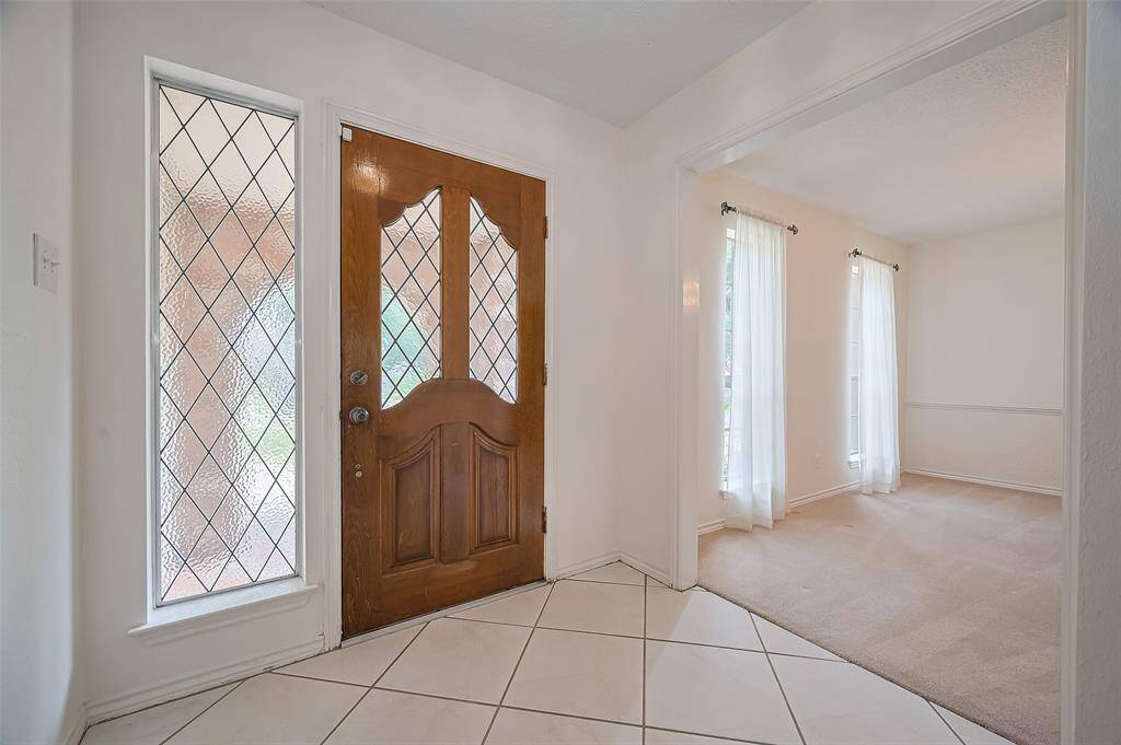 Lovely front door with rainglass leaded glass and side-light window offers privacy and charm. Guests are welcomed into a tile foyer with formal living on one side and formal dining on the other, creating a classic and inviting layout.