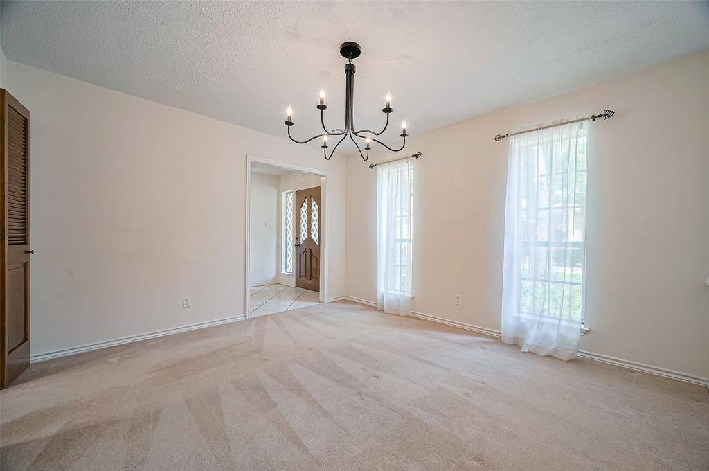 On the opposite side of the foyer is a formal dining room featuring two windows that overlook the front yard. The room is highlighted by an updated wrought iron chandelier, adding a touch of sophistication. Doors could be added off the foyer if one wanted to repurpose this space, making it easily adaptable to a home office or other needs depending on a family’s lifestyle.