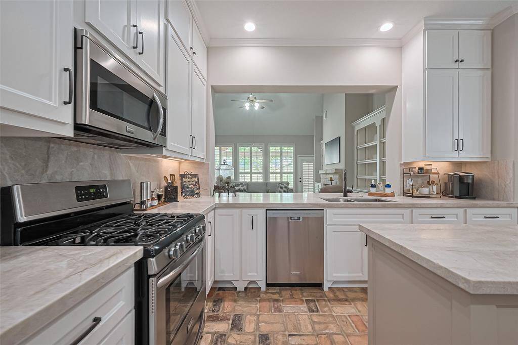 BEAUTIFULLY remodeled kitchen with classy quartzite countertops & backsplash, custom cabinets & walk-in pantry for plenty of storage, and open to the living room