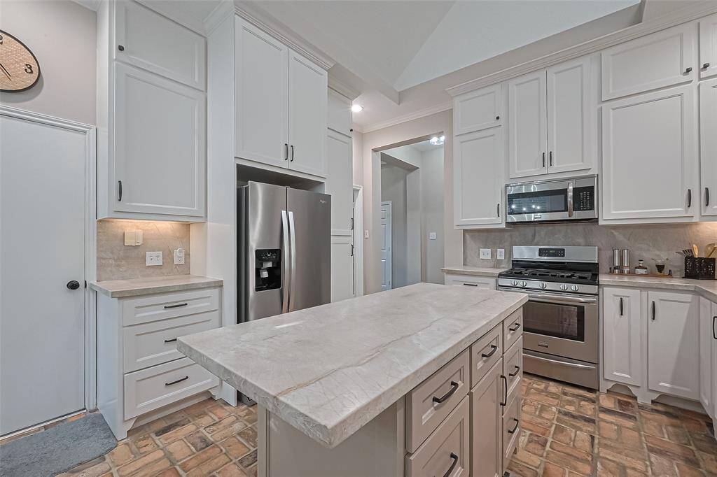 BEAUTIFULLY remodeled kitchen with classy quartzite countertops & backsplash, custom cabinets & walk-in pantry for plenty of storage, and open to the living room