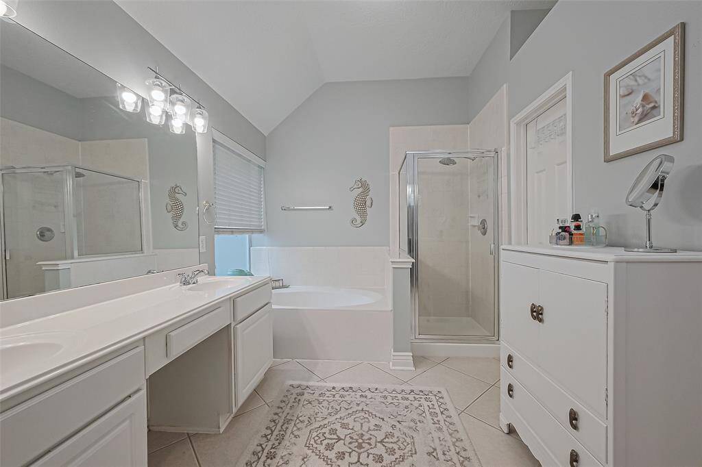 Primary bath with double sinks, soaking tub, separate shower, and large walk-in closet