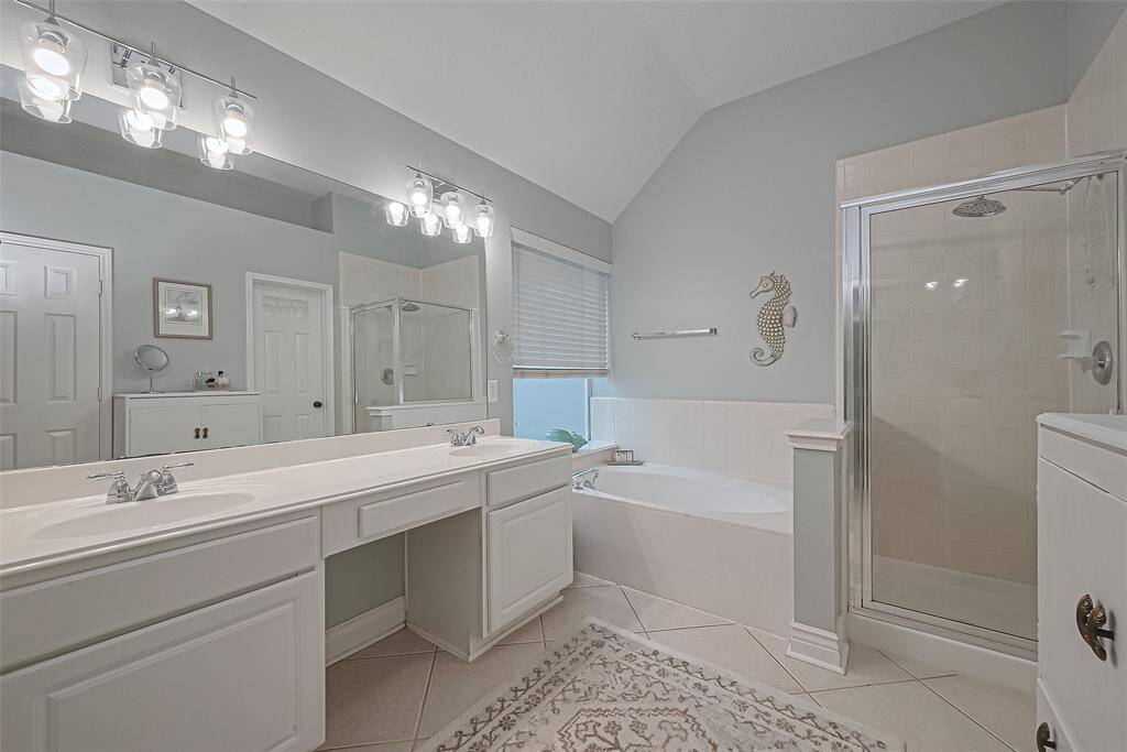 Primary bath with double sinks, soaking tub, separate shower, and large walk-in closet