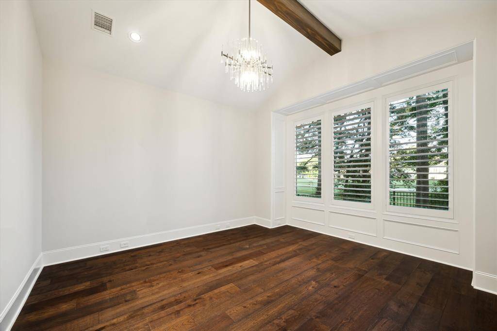 A tall pitched ceiling with dark beam, wood floors and custom lighting bring height and a dramatic flair to your luxurious primary bedroom.