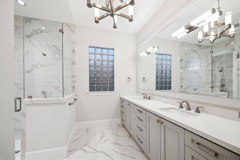 The primary en suite bathroom is a serene retreat, designed for relaxation and luxury. A spacious walk-in shower with sleek tilework offers a spa-like experience, while the elegant double vanities provide ample space for morning routines. Expansive countertops ensure effortless convenience, allowing for stylish organization and functionality. Soft lighting, refined finishes, and thoughtful details create an ambiance of tranquility, making this bathroom the perfect haven to unwind at the end of the day.