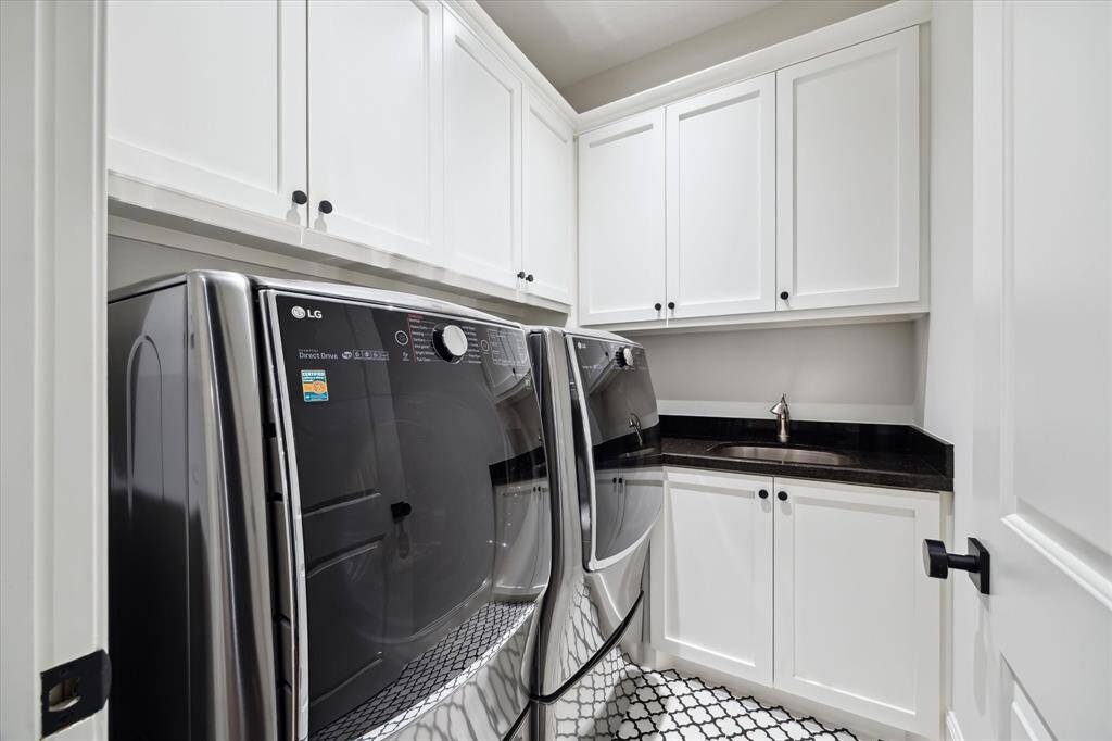 The laundry room with utility sink, custom cabinets and high-end washer/dryer makes having a fresh start easy!