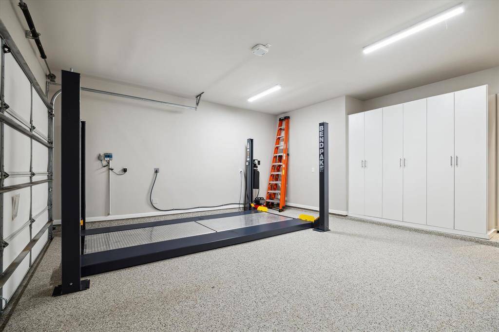 This spacious 2-car garage with finished floors and built-in cabinets is the envy of all neighbors with the newly installed Bendpak Car Lift with air compressor.