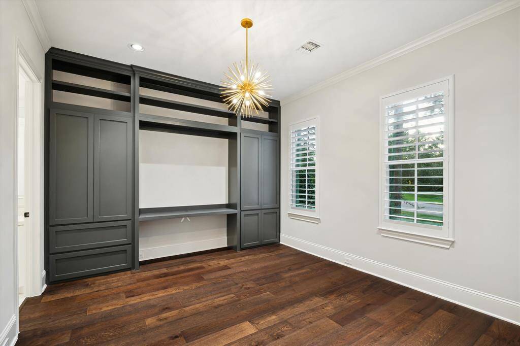 Designed for versatility, this sophisticated home office seamlessly transforms into a luxurious guest retreat with its discreetly placed walk-in closet. Rich wood finishes, expansive windows, and custom-built shelving enhance productivity, while plush accents and elegant lighting invite comfort, making it the perfect balance of workspace and sanctuary.