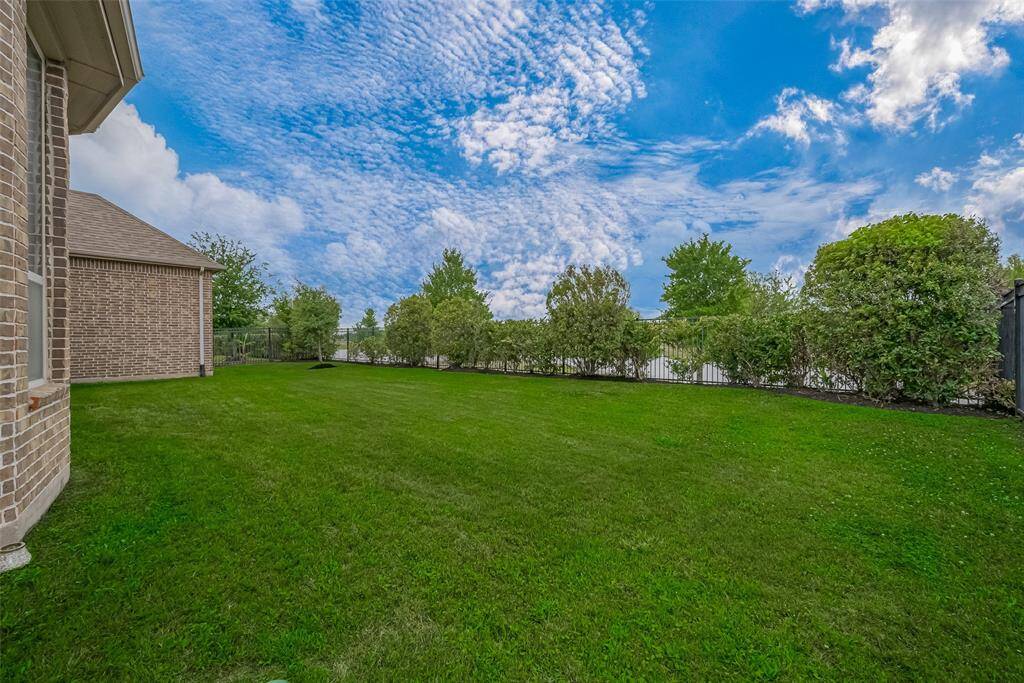 Spacious backyard with a serene view of the neighborhood lake and gated access to the walking trail.