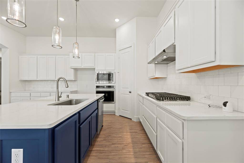 Your chef inspired kitchen awaits! Features include quartz countertops paired with a coordinating tile backsplash, stainless steel appliances, crisp white cabinets, recessed lighting, and a sprawling island with breakfast bar seating.