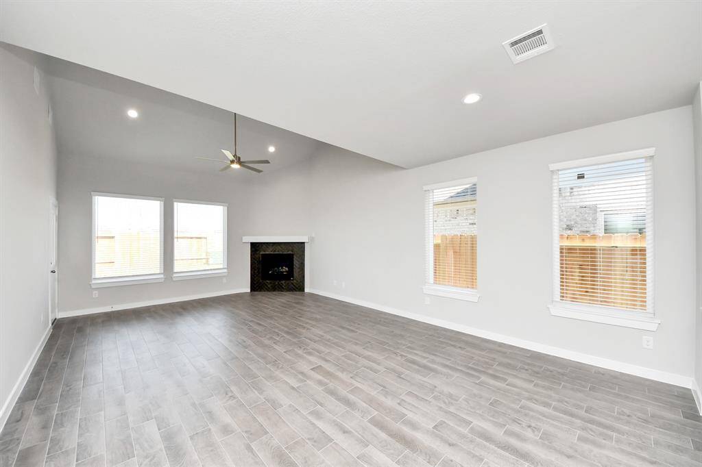 Welcome family and guests to your charming living room! With its high ceilings, recessed lighting, ceiling fan, custom paint, beautiful flooring, and large windows that let in abundant natural light, this room is perfect for gatherings. Sample photo of completed home with similar floor plan. Actual colors and selections may vary.