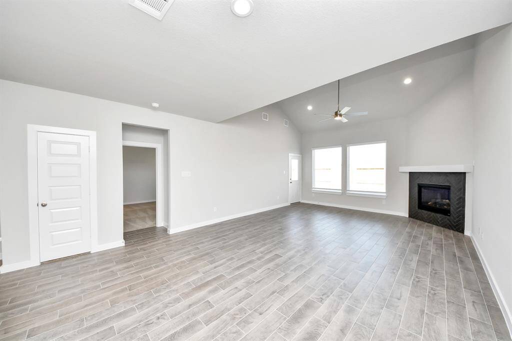 Family room flooded with natural light through the expansive windows.  The premium tile flooring adds a touch of luxury to the space, creating the perfect setting for relaxing moments and cherished gatherings with loved ones. Sample photo of completed home with similar floor plan. Actual colors and selections may vary.