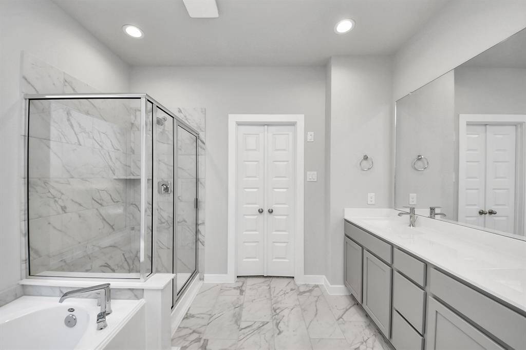Delight in a spacious walk-in shower enveloped in stylish tile surround and unwind in a separate garden tub adorned with custom detailing. Sample photo of completed home with similar floor plan. Actual colors and selections may vary.