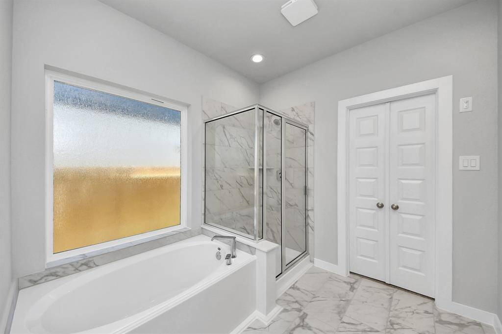 This additional view of the primary bath features a walk-in shower with the tile surround and separate garden tub perfect for soaking after a long day. Sample photo of completed home with similar floor plan. Actual colors and selections may vary.