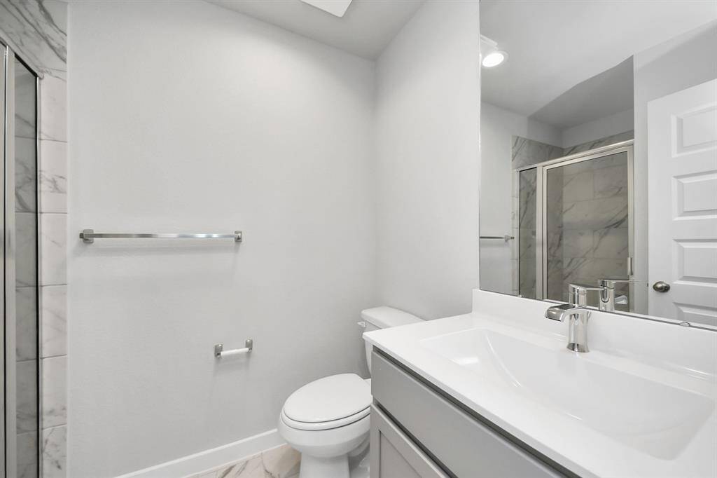 Secondary bath features tile flooring, walk-in shower with tile surround, light stained wood cabinets, beautiful light countertop. Sample photo of completed home with similar floor plan. Actual colors and selections may vary.