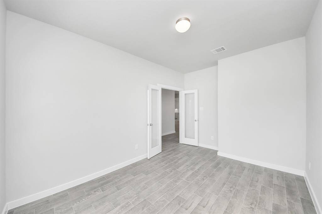 Experience the perfect blend of sophistication and warmth in this home office, boasting elegant wood-look tile flooring and flooded with natural light from expansive windows and French doors. Sample photo of completed home with similar plan. Actual colors and selections may vary. Call for more info.