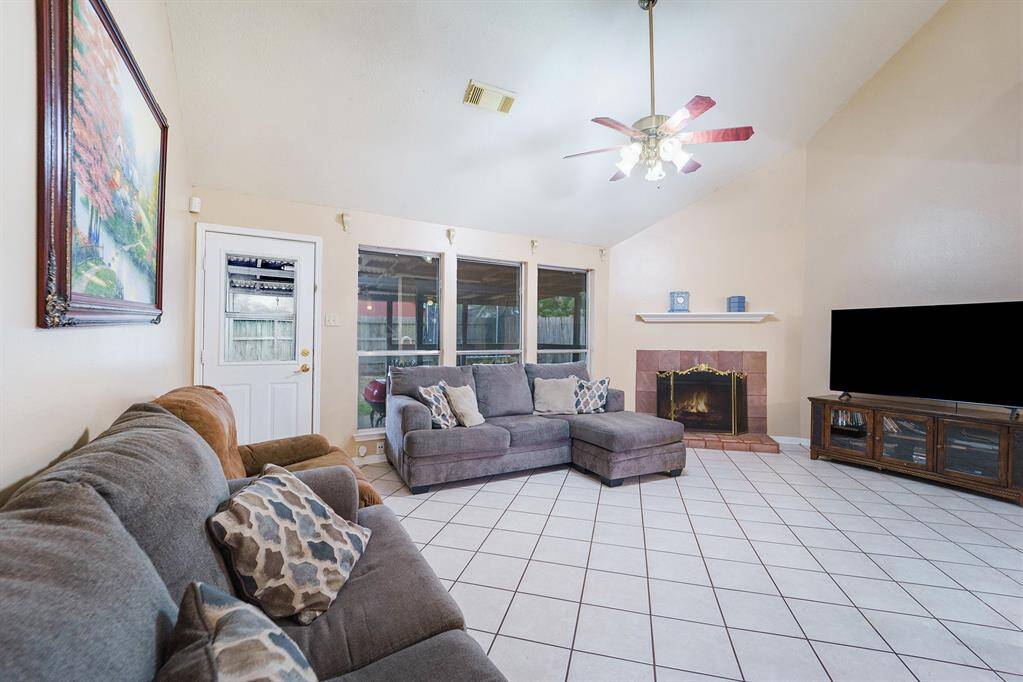 Spacious living room showcases high ceilings, a cozy fireplace, and overlooks the backyard.